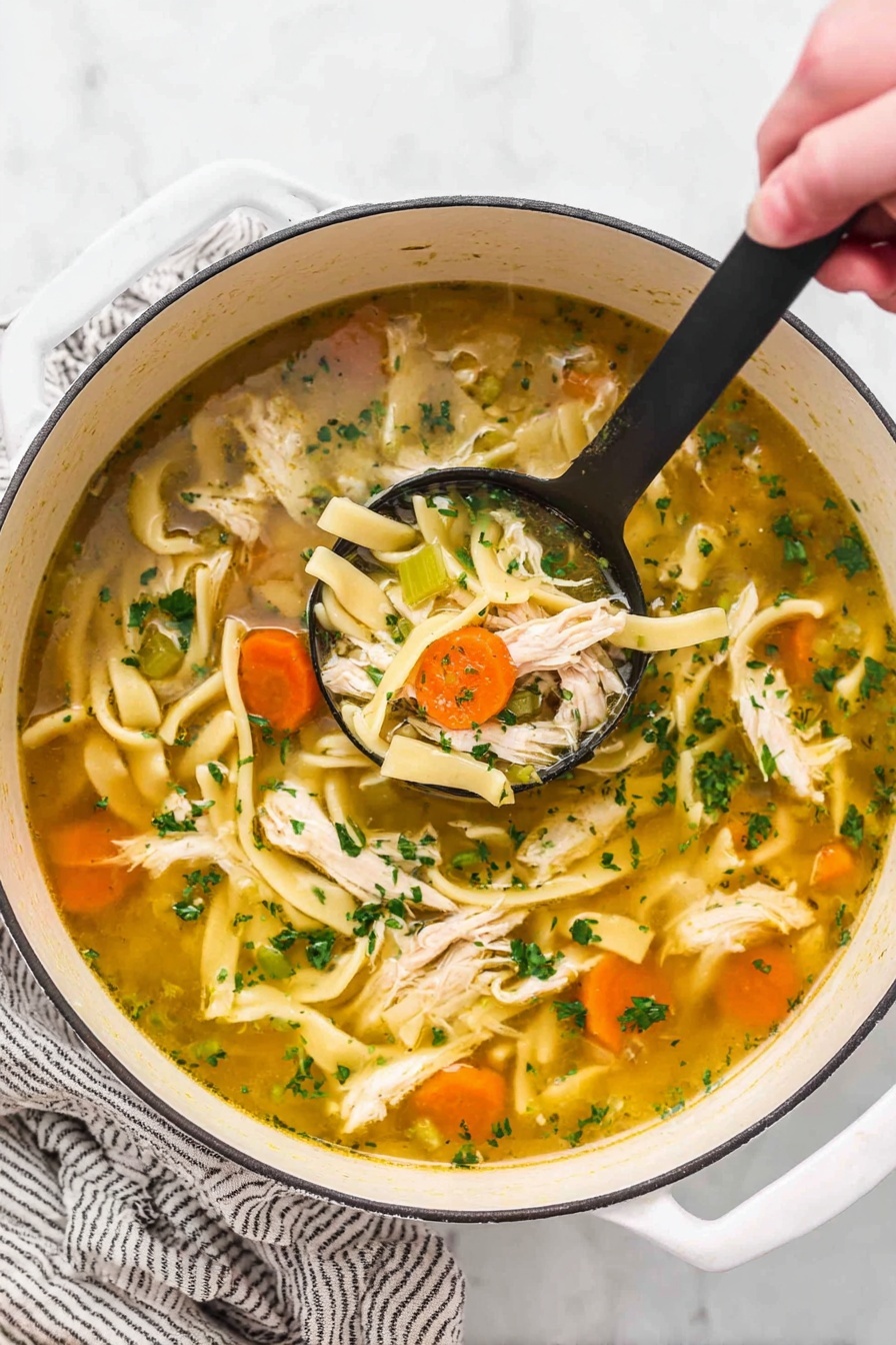 A close-up view of chicken noodle soup in a white bowl on a white marbled surface. The soup has a clear broth with chopped green herbs floating throughout. A black ladle is lifting a scoop containing shredded white chicken pieces, bright orange carrot rounds, pale green celery slices, and pale yellow wide noodles. More carrots, noodles, and herbs can be seen in the broth around the ladle. The textures show soft chicken, tender vegetables, and slippery noodles in the warm broth. Photo taken with an iphone --ar 2:3 --v 7