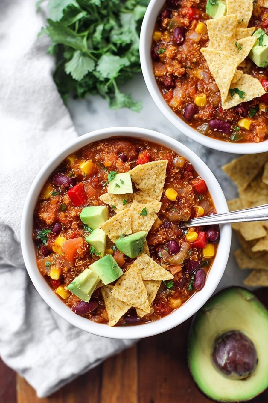 A woman's hand with red nail polish is holding a triangular light beige tortilla chip close to the camera. The tip of the chip is covered with a colorful mix of small black beans, yellow corn kernels, green avocado chunks, and some reddish-orange sauce with a slightly textured surface. In the background, a white bowl filled with the same mix and scattered avocado pieces is visible, all set on a white marbled textured surface. The image emphasizes bright colors and a fresh, mixed texture of the food. photo taken with an iphone --ar 2:3 --v 7