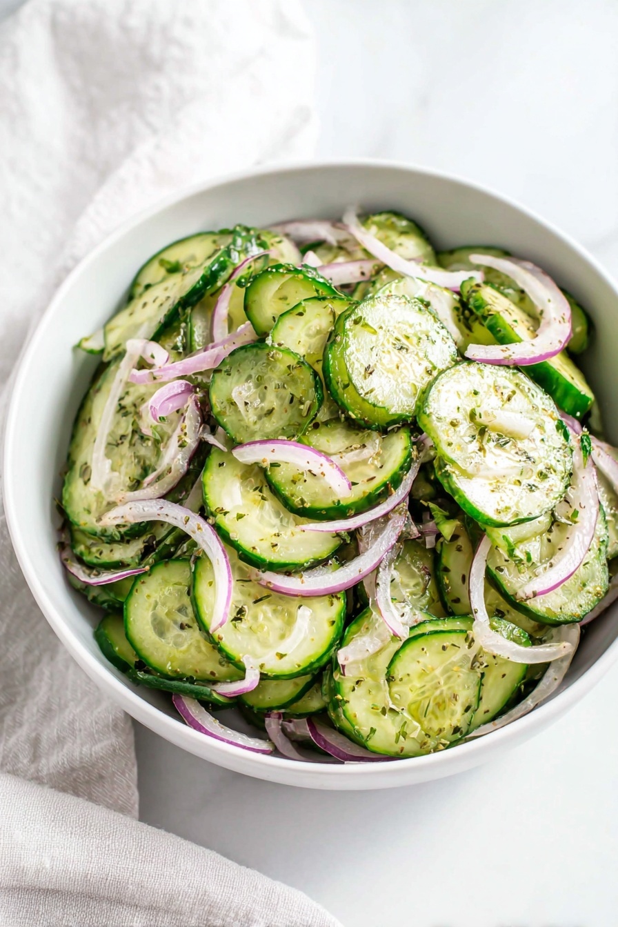 In a white bowl on a white marbled surface, there is a cucumber salad made of many thin round slices of green cucumber layered and mixed with thin strips of light purple and white onion spread throughout. The cucumber slices have a fresh, moist texture with green skin edges, while the onion strips add contrast in color and texture. Small specks of herbs and seasoning are scattered evenly on top, giving the salad a light seasoning look. A light cloth is slightly visible in the background. Photo taken with an iphone --ar 2:3 --v 7