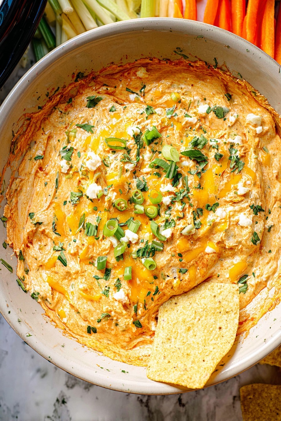 The image shows a black slow cooker filled with creamy orange cheese dip that has a slightly melted look. On top of the dip, there are pieces of melted yellow cheese mixed with green chopped herbs and green onion slices spread evenly. A few light yellow triangular chips are partially dipped into the cheese, resting near the right edge of the dip. Around the slow cooker, you can see plates with light-colored crackers, orange carrot sticks, green celery sticks, and some leafy green garnish, all placed on a white marbled surface. photo taken with an iphone --ar 2:3 --v 7
