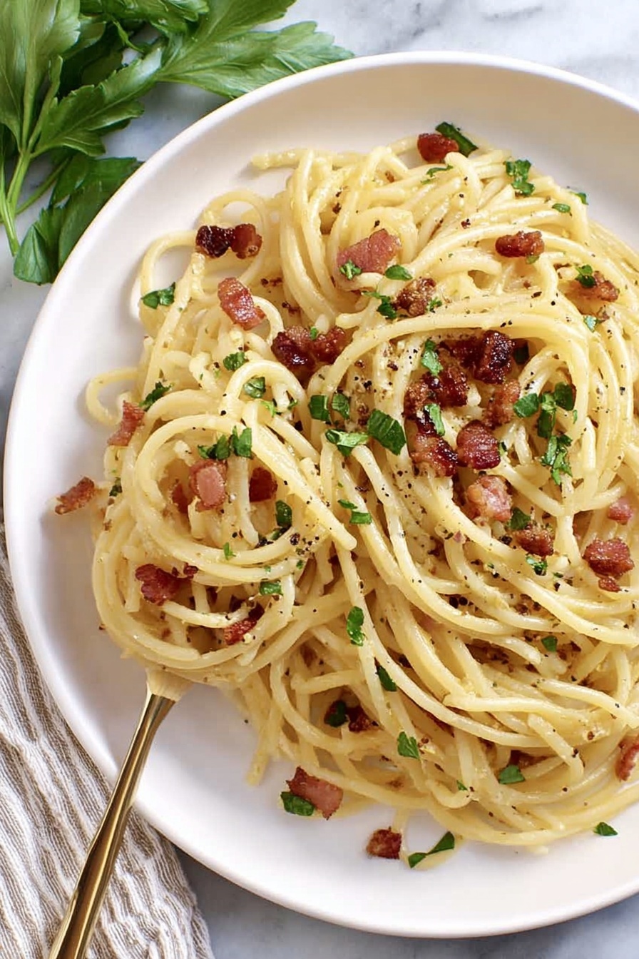 A plate with a single layer of spaghetti pasta that is pale yellow and shiny, mixed with small pieces of crispy brown bacon scattered throughout. Finely chopped green herbs are sprinkled on top, along with some black pepper dots. A silver fork lifts some spaghetti from the right side of the plate. The plate is white and sits on a white marbled surface with a few green herb leaves in the background. Photo taken with an iphone --ar 2:3 --v 7