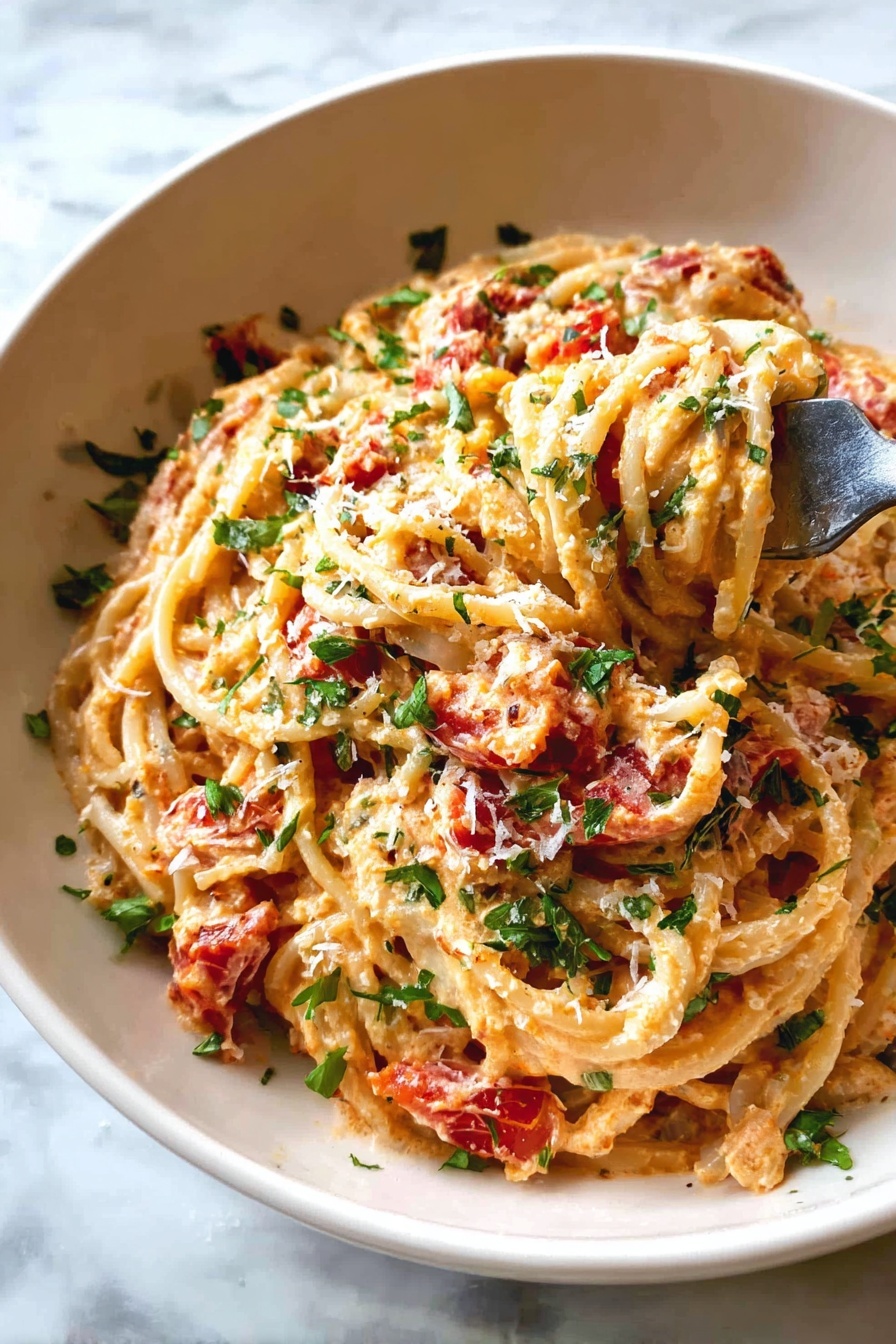 A white bowl filled with creamy spaghetti pasta covered in a light orange sauce mixed with chunks of red tomatoes and green herbs scattered throughout. The pasta strands are tangled together with some lifting upward, held by a fork with a silver handle. The dish is sprinkled with finely chopped green parsley and grated white cheese. The bowl sits on a surface with a white marbled texture. photo taken with an iphone --ar 2:3 --v 7