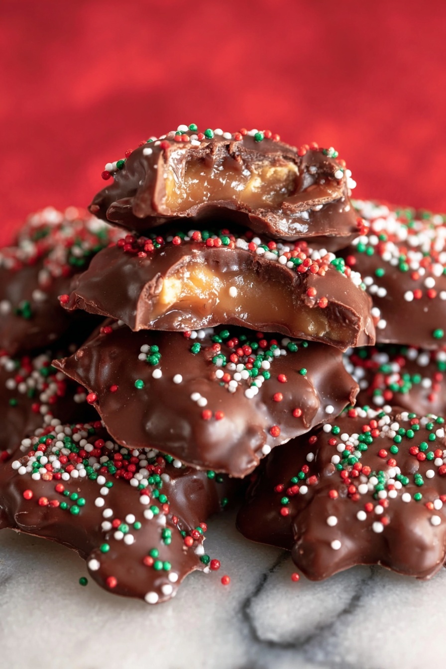 A white bowl decorated with small Christmas images is filled with multiple clusters of thick, shiny milk chocolate coated nuts or candies, each topped with small red, white, and green round sprinkles. The bowl sits on a red cloth with a subtle pattern on a white marbled surface, surrounded by golden-wrapped candies and some whole pecans. To the left, there is a white ceramic mug with a red knitted pattern design. The scene looks cozy and festive. photo taken with an iphone --ar 2:3 --v 7