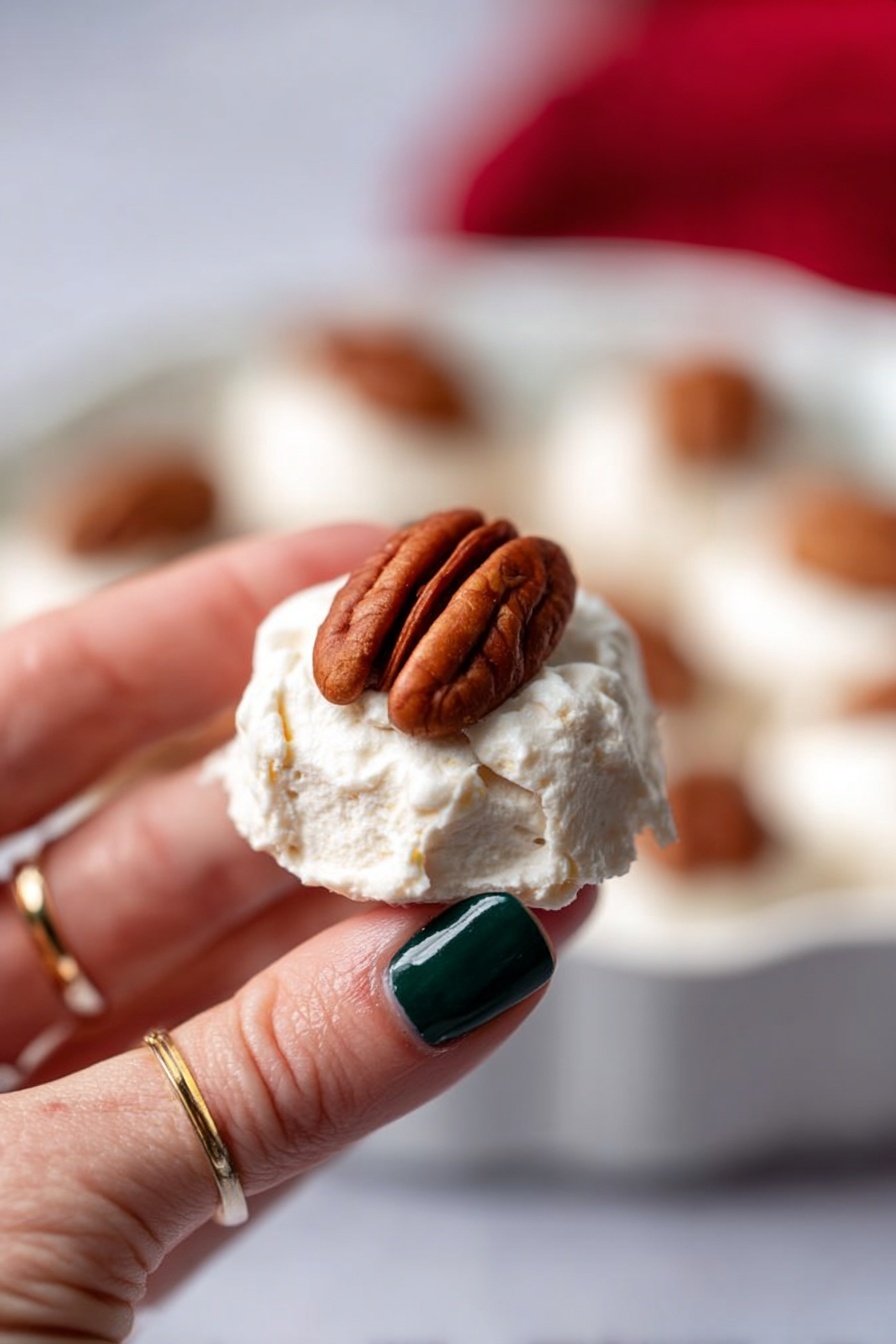 The image shows a baking tray lined with parchment paper with twelve small round white meringue nests arranged neatly in four rows of three. Each meringue is smooth and slightly glossy, with a soft texture and a small pecan half placed boldly in the center of every nest. The background surface is a white marbled texture, and the meringues stand out clearly against the pale backdrop, highlighting their delicate and airy appearance. photo taken with an iphone --ar 2:3 --v 7