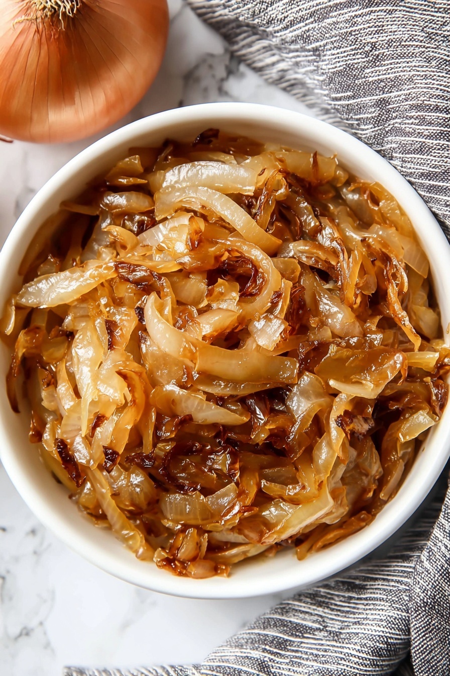 A close-up view of caramelized onions showing one main layer of soft, thinly sliced onions cooked to a mix of light golden brown and deeper amber colors. The onions have a shiny, slightly sticky texture with some darker caramel spots and gentle curls on the edges, creating a rich layered look from overlapping slices. The background visible is a white marbled surface. photo taken with an iphone --ar 2:3 --v 7