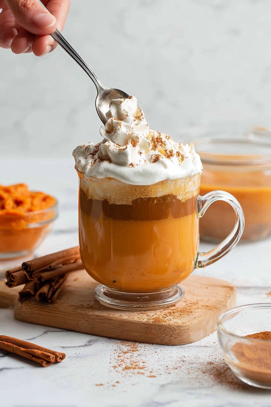 A woman's hand is pouring a bright orange-yellow liquid from a clear glass cup into a silver pot that contains a smooth, creamy brown liquid. The pot sits on a black metal cooling rack, and the whole setup is on a white marbled surface. The shiny pot reflects light and shows the rich texture of the liquids inside. Photo taken with an iphone --ar 2:3 --v 7