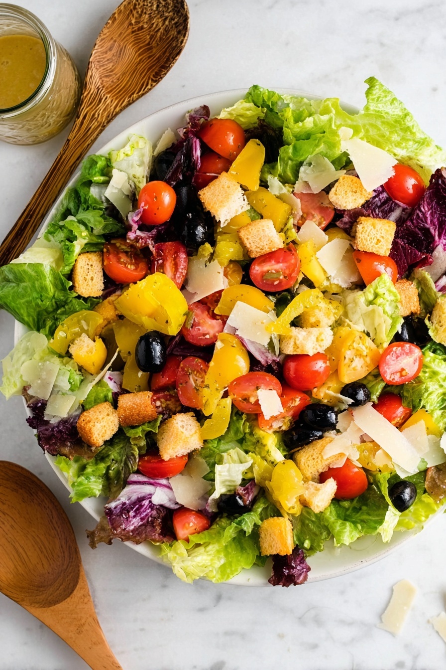 A white plate filled with fresh salad layers including green and purple lettuce leaves as the base. On top, there are bright red cherry tomato halves, black olives, and yellow pepperoncini peppers scattered throughout. Small golden brown croutons add texture, and thin, pale yellow cheese slices are sprinkled over everything. The plate is placed on a white marbled surface with wooden salad utensils resting on the left side and a glass jar of dressing nearby. Photo taken with an iphone --ar 2:3 --v 7