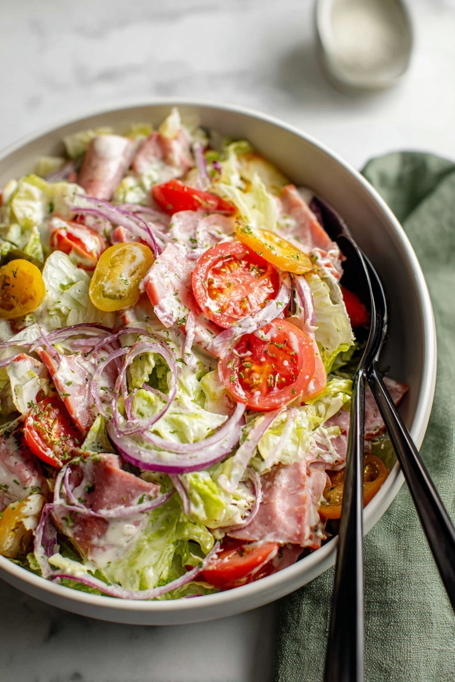 A large white bowl filled with a mixed salad showing many layers, including light green lettuce leaves as the base, evenly spread thin slices of pink ham, and round slices of red tomato. Scattered on top are thin slices of purple onion and pieces of yellow pepper. The salad is coated lightly with a creamy white dressing and sprinkled with small green herbs. Two black spoons rest inside the bowl on a white marbled surface with a green cloth partially visible on the right side. Photo taken with an iphone --ar 2:3 --v 7