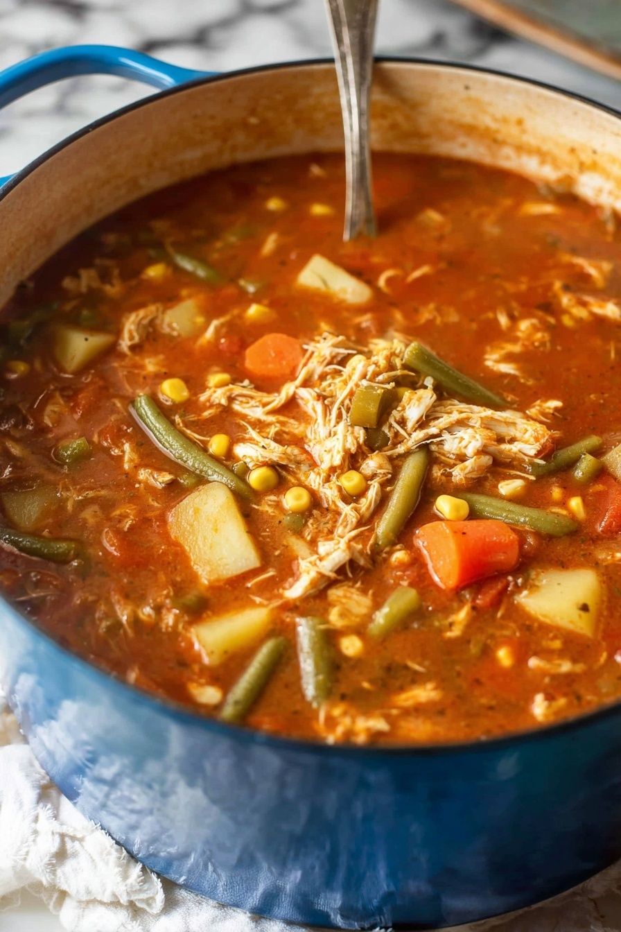 A large blue pot filled with a thick stew containing visible layers of shredded white chicken, green beans, orange carrot slices, yellow corn kernels, and light yellow potato chunks all mixed in a rich reddish-brown broth with small bits of tomato. A silver spoon is partially visible in the stew. The pot sits on a white cloth on a surface with a white marbled texture in the background. Photo taken with an iphone --ar 2:3 --v 7